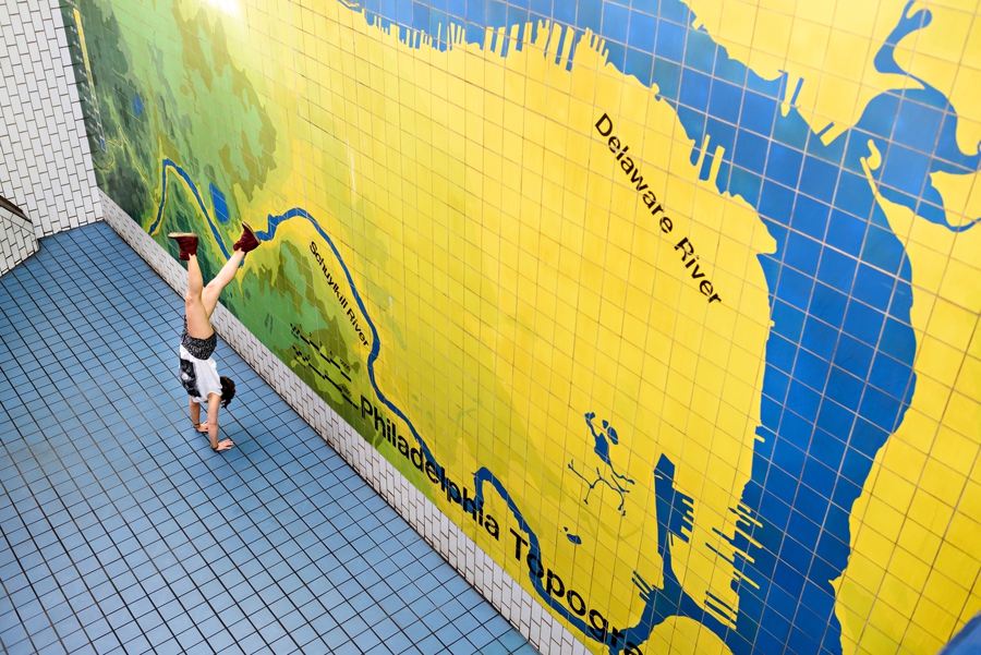 A woman doing a handstand in the subway in philadelphia.